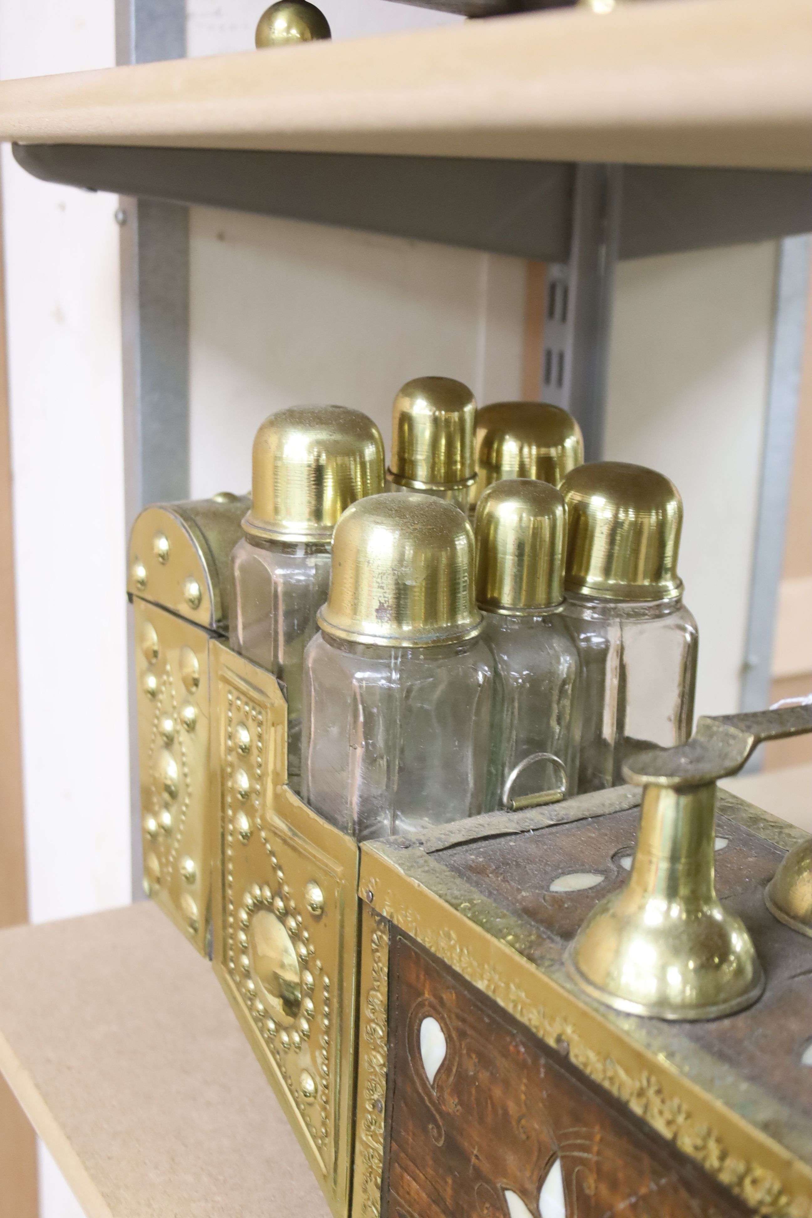 An Indian brass & hardwood shoe shiner's set, with twelve flasks. 57cm. long. 15cm. deep. 28cm. high